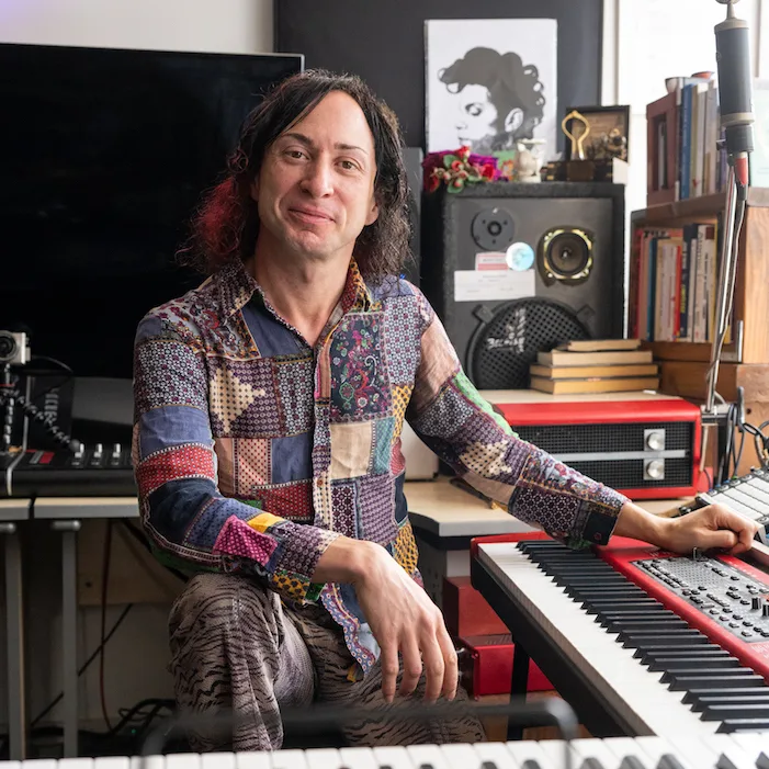 BexX, Bristol singing teacher, seated at a keyboard in their studio